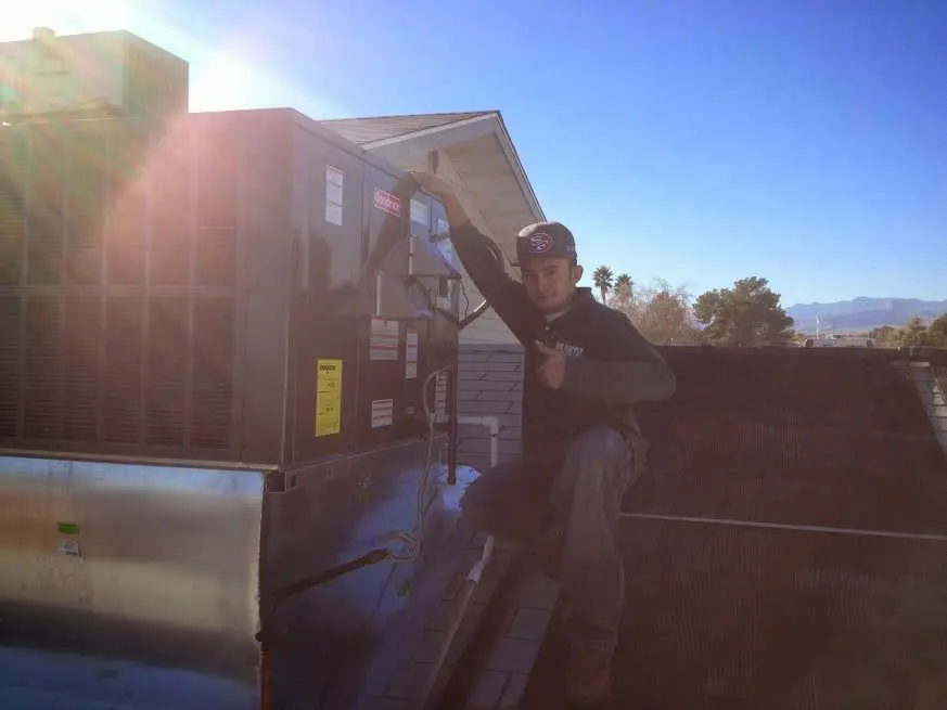HVAC technician performing AC Tune-Up on a rooftop unit in Sutton